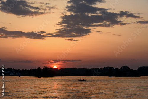 Silhouette of fishing ship on the embankment of the Angara river in sunset sun