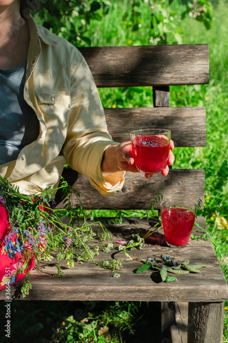 Woman sitting on bench in garden drinking red berries juice