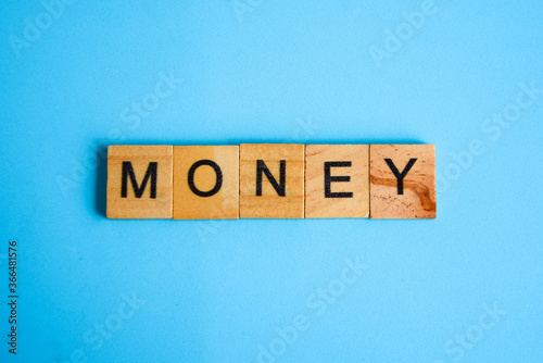 Wooden blocks with the lettering word Money on top of blue background. business and finance concept