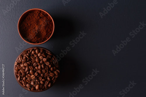 Roasted and ground coffee beans in round bowls on dark blue table background. Close-up, top view, copy space. Coffee shop, morning, barista workplace concept