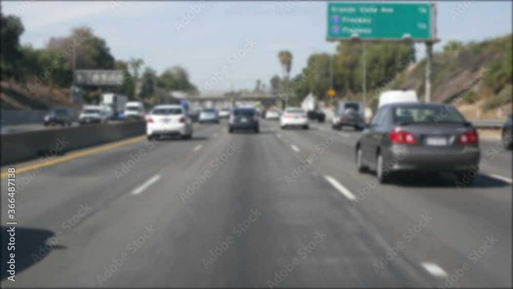 Driving on intercity freeway in Los Angeles, California USA. Defocused view from car thru glass windshield on busy interstate highway. Blurred suburb multiple lane driveway. Camera inside auto in LA. Driving on intercity freeway in Los Angeles, California USA. Defocused view from car thru glass windshield on busy interstate highway. Blurred suburb multiple lane driveway. Camera inside auto in LA.