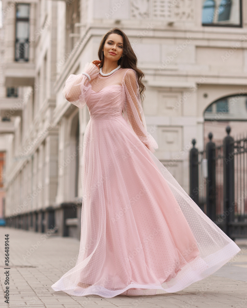 Young beautiful woman wearing long pink dress. Outdoor fashion full length portrait. Young beautiful woman wearing long pink dress. Outdoor fashion full length portrait.