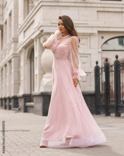 Young beautiful woman wearing long pink dress. Outdoor fashion full length portrait.