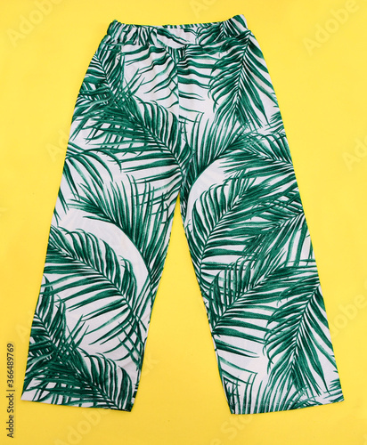 Summer culottes trousers with tropical print close up photo on yellow background. Female trousers culotte in tropical print