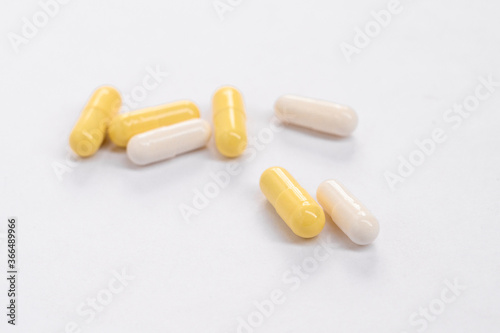 White pills and yellow capsules of drugs lie on white background. Top view. Copy space. Isolated. Concept pharmacy, medicine, healthcare, painkillers, drug, abuse. panoramic