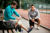 Young men exercising on a race track. Two young friends training outdoors.	