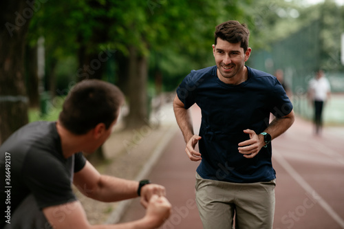 Young men training on a race track. Two young friends running on the athletics track 