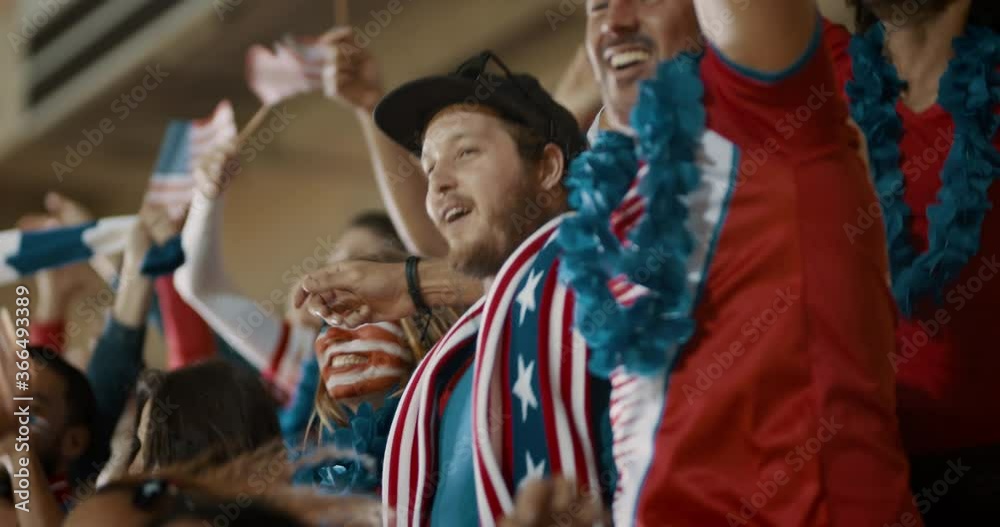 Excited fans celebrating in stands. American soccer supporters cheering over a goal in stadium.
