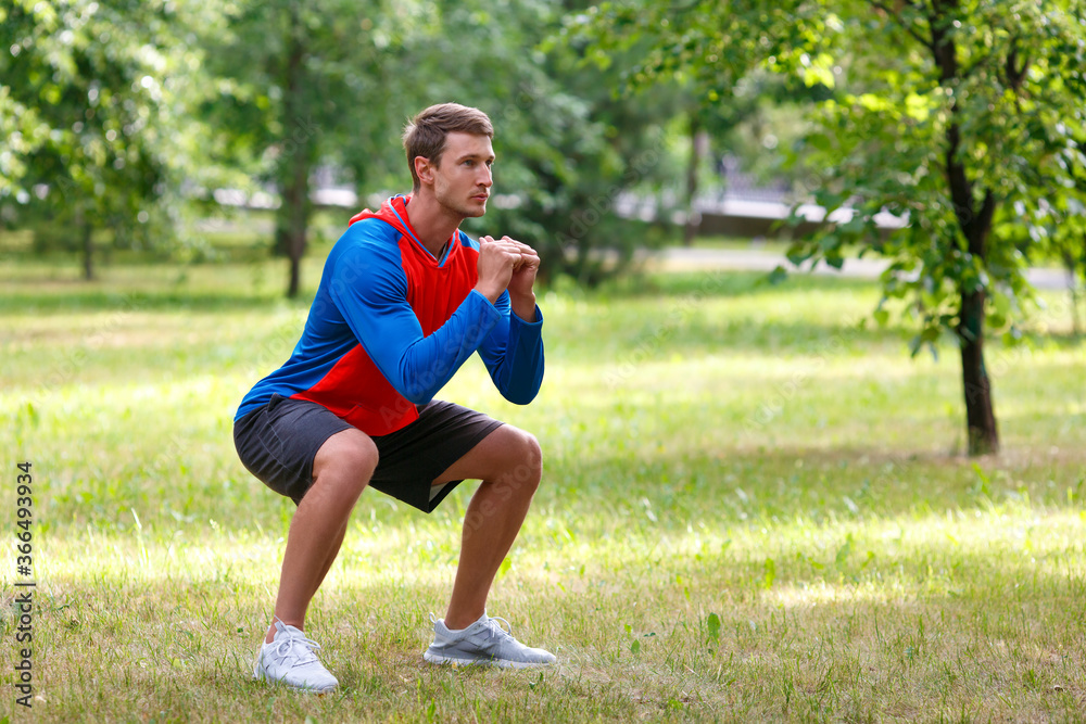 Young attractive man squatting outdoor in the park. Young attractive man squatting outdoor in the park.