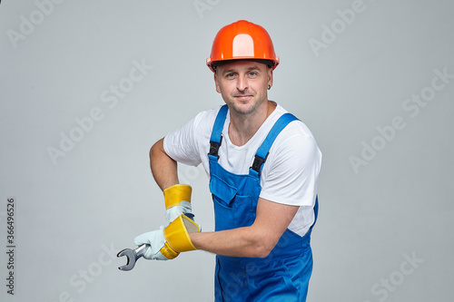 adult man in a construction helmet does his job with a wrench.