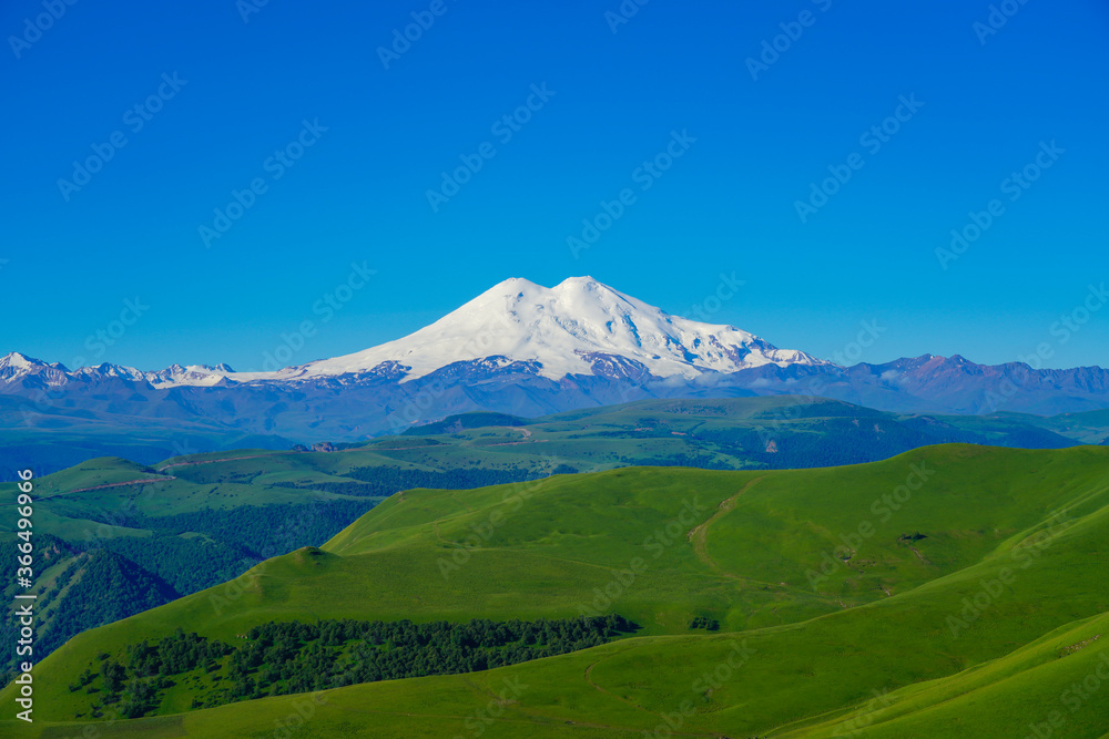 Green Meadow Hills background Elbrus at a Summer Day. North Caucasus, Russia