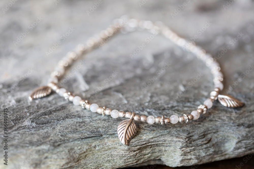 Beautiful female bracelet with moon stone on neutral rocky background Beautiful female bracelet with moon stone on neutral rocky background