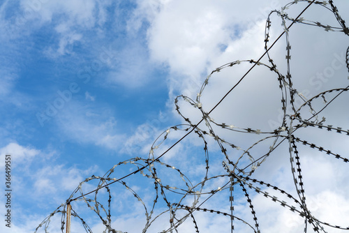 Barbed wire against the sky. Metal fence. Restriction of freedom.