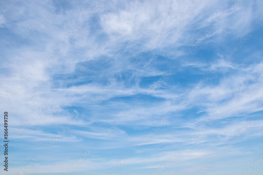 Fluffy white clouds float across the blue sky on a clear sunny summer or spring day. Empty space for inscriptions, form. Cyan or teal 
background sky. Low angle view