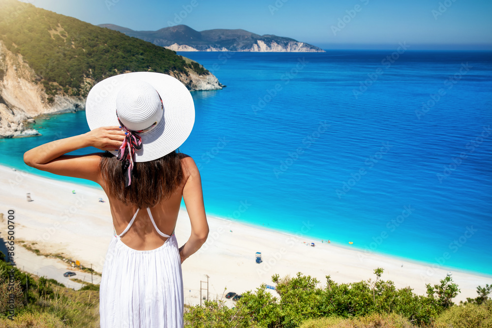 Touristin mit weißem Sommerkleid schaut auf den berühmten Strand von Myrtos auf der ionischen Insel Kefalonia, Griechenland