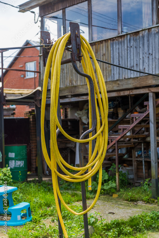 yellow garden hose hanging from a metal pole in the backyard yellow garden hose hanging from a metal pole in the backyard