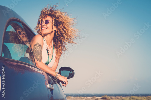 Attractive curly blonde young woman smile and enjoy the wind outside the car - concept of beauty and travel for happy and cheerful caucasian people - alternative lifestyle female feel the freedom joy © simona