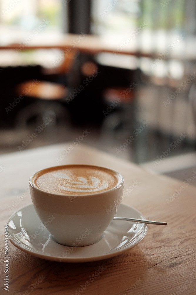 Breakfast in the cafe. Beautiful white mug with cappuccino or latte coffee on a wooden table. View from above. 