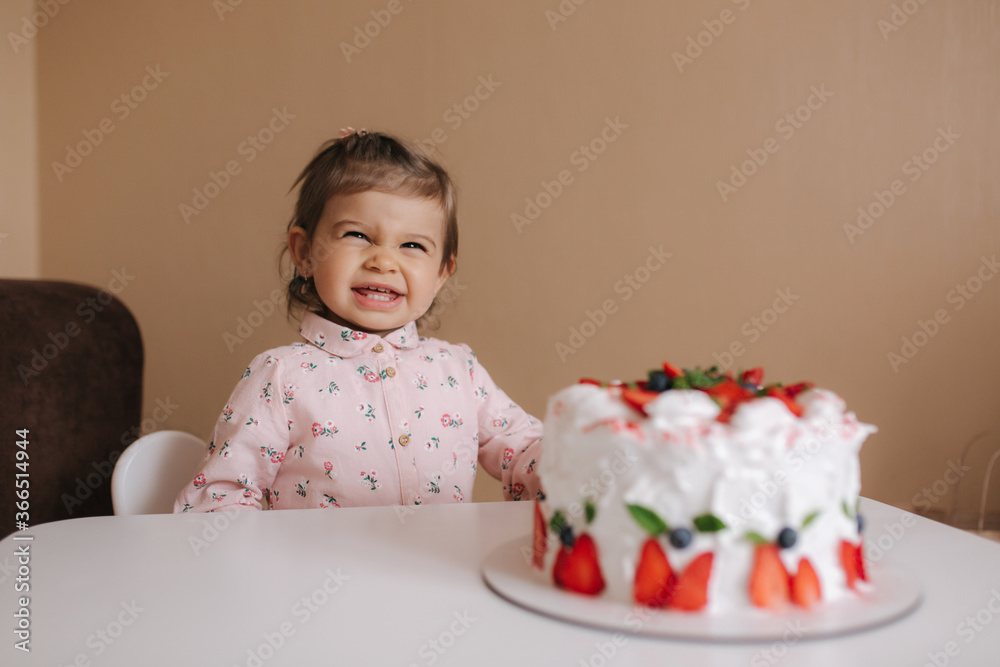 Cute little girl one and a hulf year old stand by delicious birthday cake. Eighteen month old girl verry happy and laughs. Vegetarian food. Lactose free and gluten free. Cute little girl one and a hulf year old stand by delicious birthday cake. Eighteen month old girl verry happy and laughs. Vegetarian food. Lactose free and gluten free.