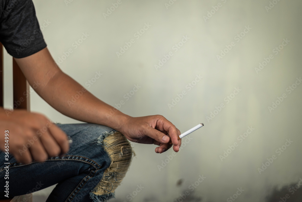 man sit on chair and holds a cigarette for smoking   behind the wall. concept for crime, illness, narcotic.