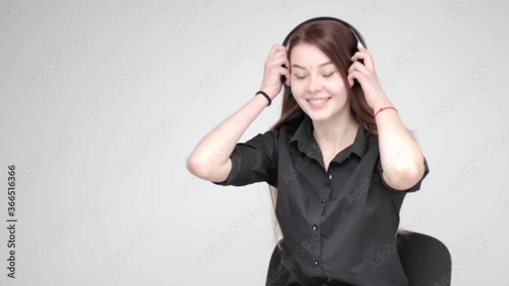 Good looking young girl with long hair putting black wireless headphones on and using white tablet Good looking young girl with long hair putting black wireless headphones on and using white tablet
