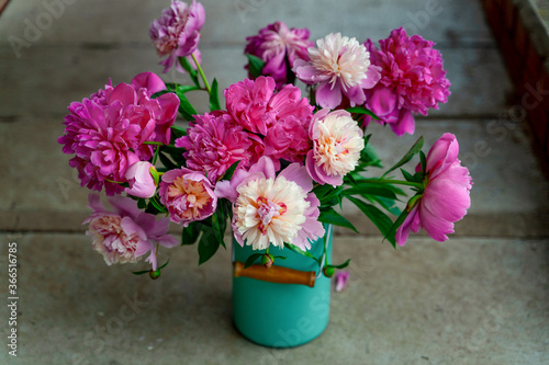 Fototapeta Naklejka Na Ścianę i Meble -  Bouquet of peony flowers in milk can on cement stairs