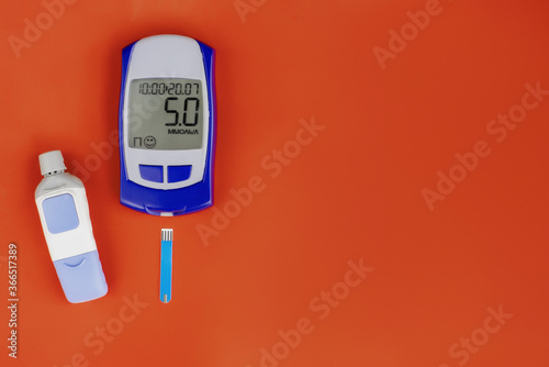 Digital glucometer and lancet pen on yellow background, close-up, flat lay. Diabetes concept. Blood glucose meter.