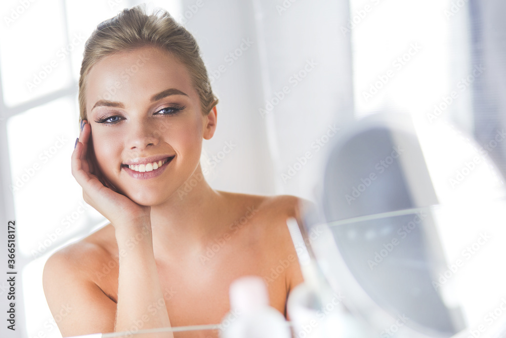 Young woman in bathrobe looking in bathroom mirror Young woman in bathrobe looking in bathroom mirror