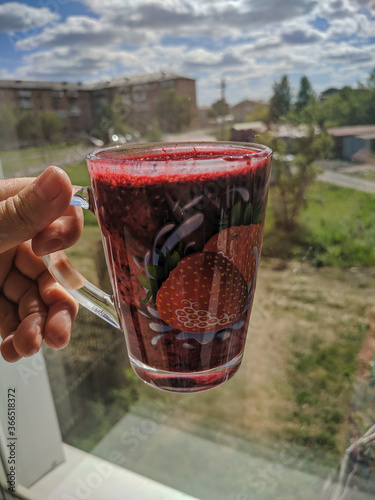 Kamen-na-Obi, Altai, Russia - May 25, 2020: Honeysuckle smoothie in a transparent glass. Vertical.