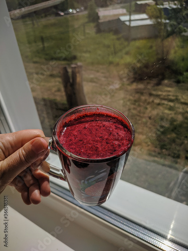 Kamen-na-Obi, Altai, Russia - May 25, 2020: Honeysuckle smoothie in a transparent glass. Vertical.