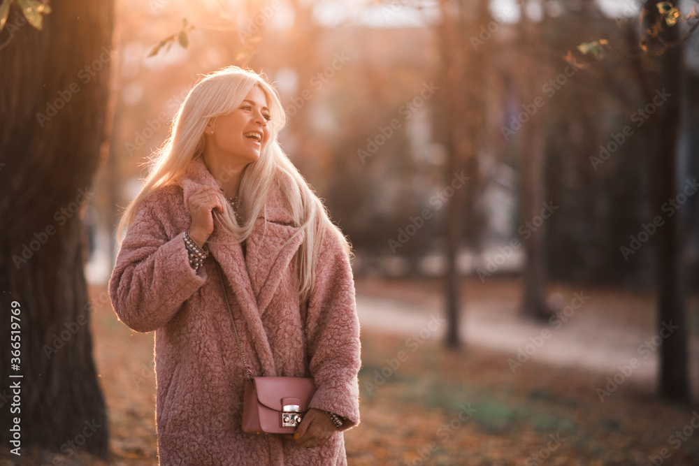Laughing blonde beautiful girl 24-25 year old wearing winter coat walking in park outdoors. Winter season. Happiness. Laughing blonde beautiful girl 24-25 year old wearing winter coat walking in park outdoors. Winter season. Happiness.