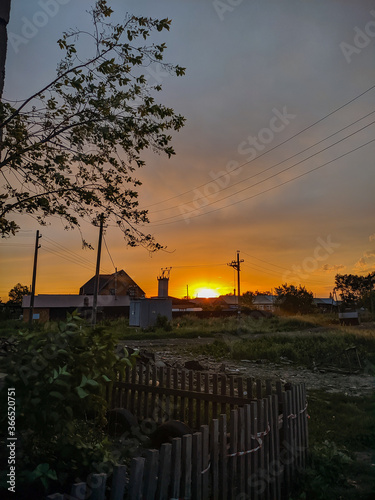 Kamen-na-Obi, Altai, Russia - May 27, 2020:    Russian village. Evening sunset on the background of houses. Vertical.