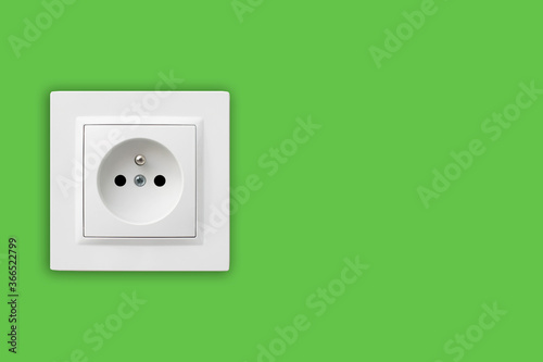 Brand new electrical socket isolated on green wall. Renovated studio apartment power supply background. Empty copy space double white plastic power outlet. Be eco and save energy.