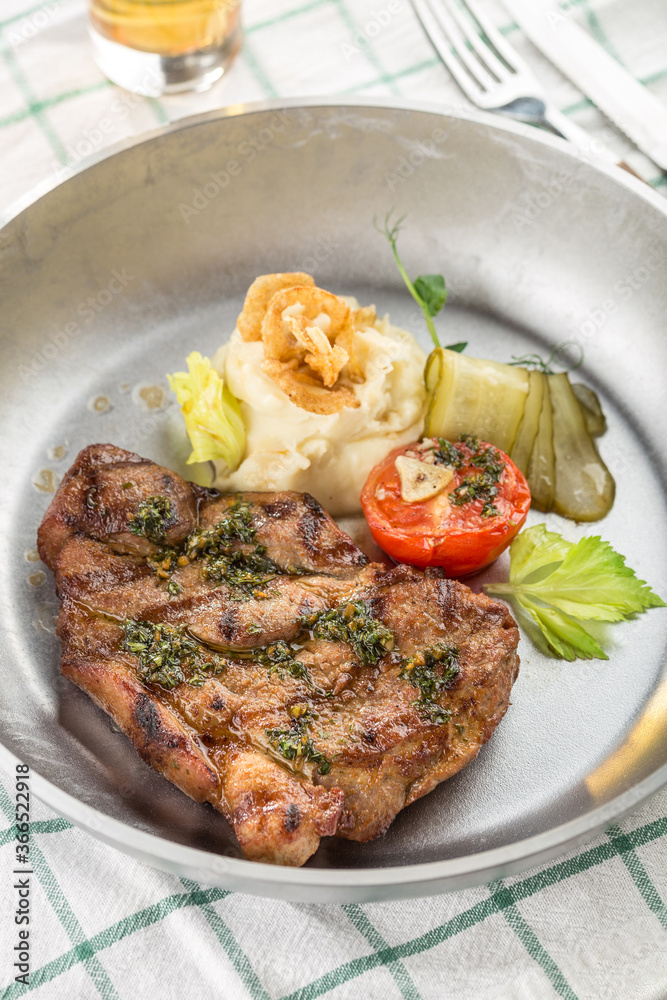 Grilled pork steak with mashed potato, pickles and glass of beer on the table Grilled pork steak with mashed potato, pickles and glass of beer on the table