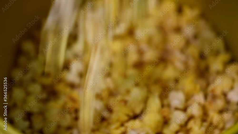 Close up shot of ready yellow caramel sweet cheese flavoured popcorn seeds falling on top of each other in plastic bowl Close up shot of ready yellow caramel sweet cheese flavoured popcorn seeds falling on top of each other in plastic bowl