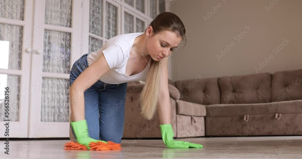 Woman in green rubber gloves use brush cleans floor. Disinfection of surfaces, general cleaning of house