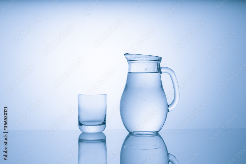 Pitcher with drinking water and a glass with a drink, blue tone Pitcher with drinking water and a glass with a drink, blue tone