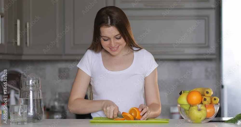 cutting orange fruit into slices with a metal knife by a woman on modern kitchen. Healthy eating, cooking, dieting and people concept. cutting orange fruit into slices with a metal knife by a woman on modern kitchen. Healthy eating, cooking, dieting and people concept.