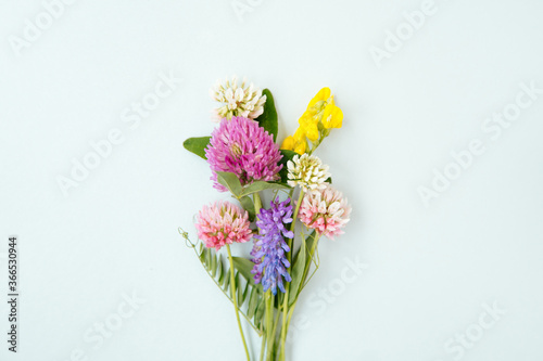 Canvas Print Small bouquet of miniature wildflowers on blue background in the centre, copyspace for summer and wedding design
