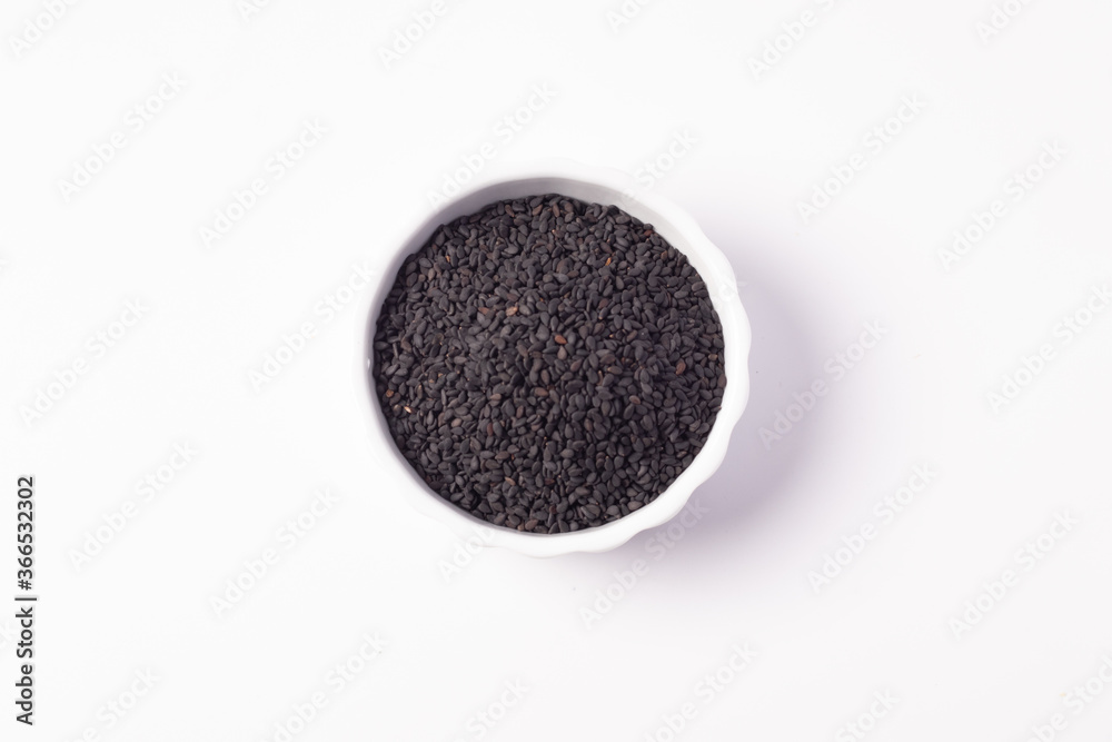 Black sesame seeds in a white ceramic cup on a white background Black sesame seeds in a white ceramic cup on a white background