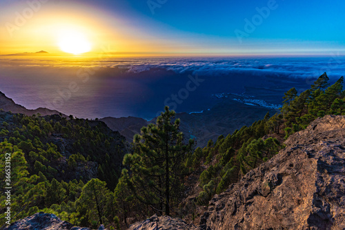 sunset from the canaries  the island of gran canaria with the roque faneque and the teide in the background bathed by a sea of clouds and the reflections and lux of the sun  in tamadaba natural park.