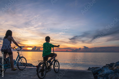 Mother and child ride a bicycle on the beach happily.