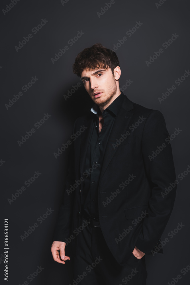 handsome man in formal wear standing with hand in pocket on black handsome man in formal wear standing with hand in pocket on black