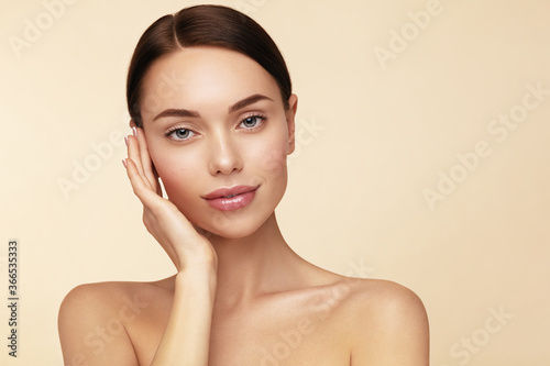Beauty treatment and skin care. Young beautiful model touching her face and looking at camera.