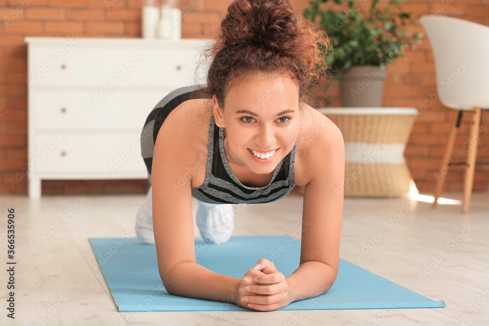 Fototapeta premium Sporty young woman training at home