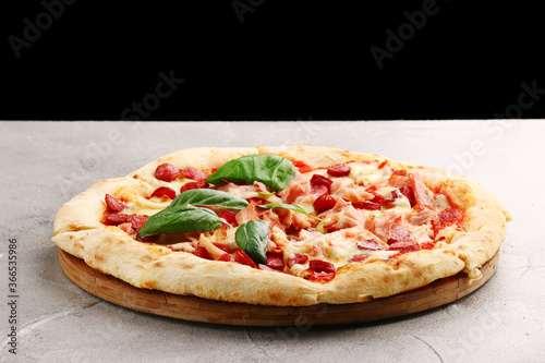 pizza with sausage and bacon closeup on light concrete or stone background