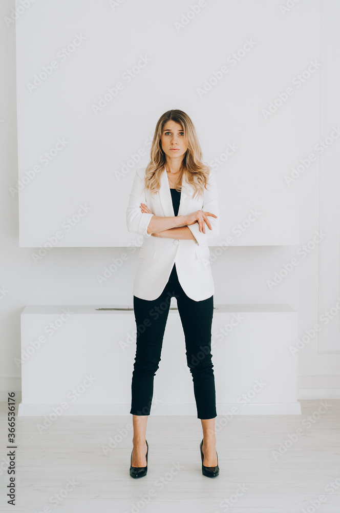 Beautiful businesswoman at the co-working. Blonde girl in a business dress against the background of a minimalistic interior. Beautiful businesswoman at the co-working. Blonde girl in a business dress against the background of a minimalistic interior.