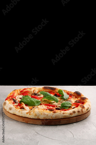 pizza with mushrooms, tomato and chicken closeup pizza with mushrooms and chicken on light concrete or stone table and black background for copy space