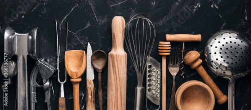 Various kitchen utensils and tools on a black stone background, banner. Top view, flat lay. Collection kitchenware. photo