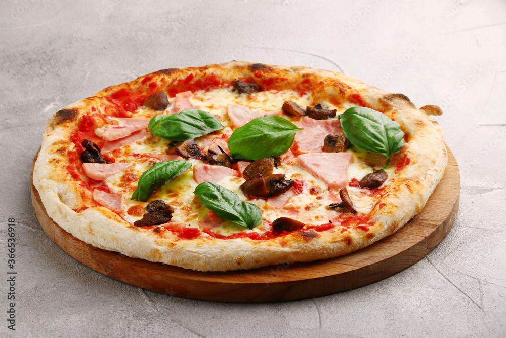 pizza with mushrooms and ham closeup on light concrete or stone table